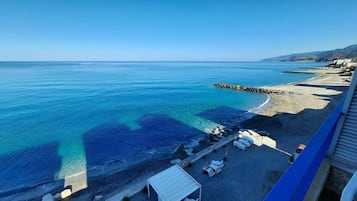 Pantai pribadi, pasir putih, kursi berjemur, dan payung pantai