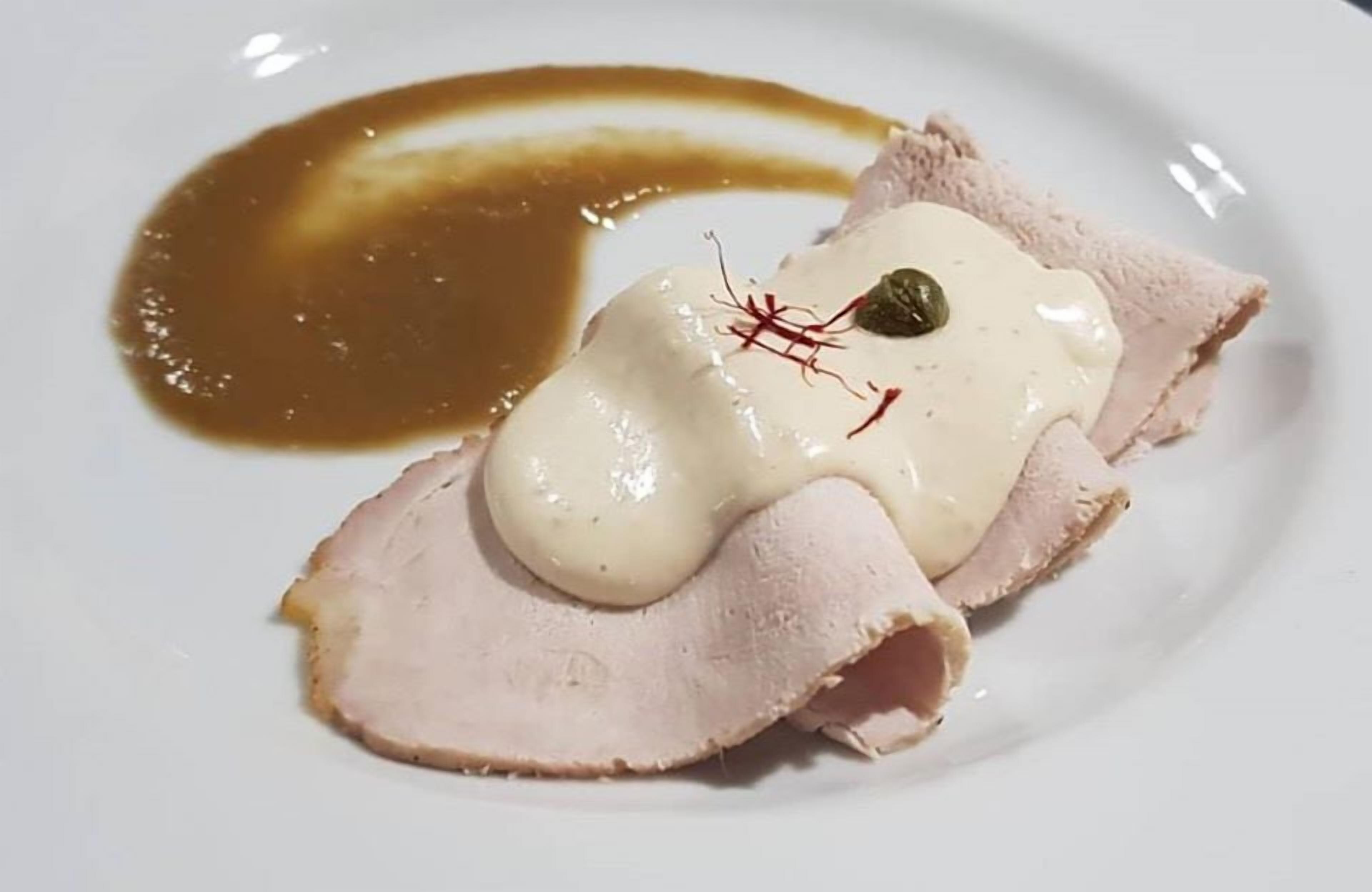 Ein Teller mit geschnittenem Fleisch und Soße.