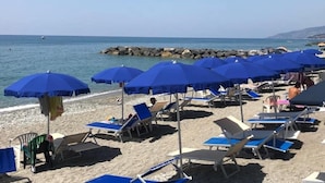 A beach with rows of blue umbrellas and sun loungers.