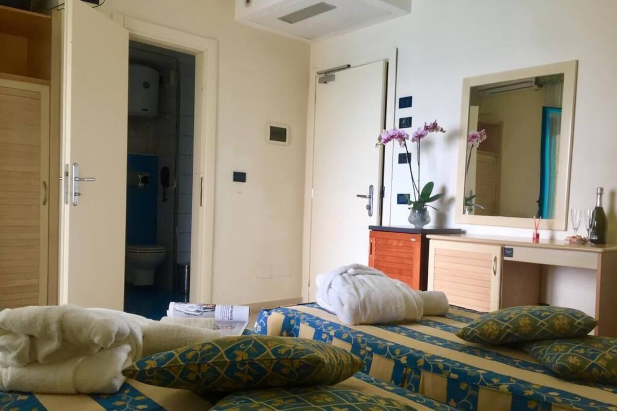 A hotel room with two beds, a bathroom, and a small kitchenette.