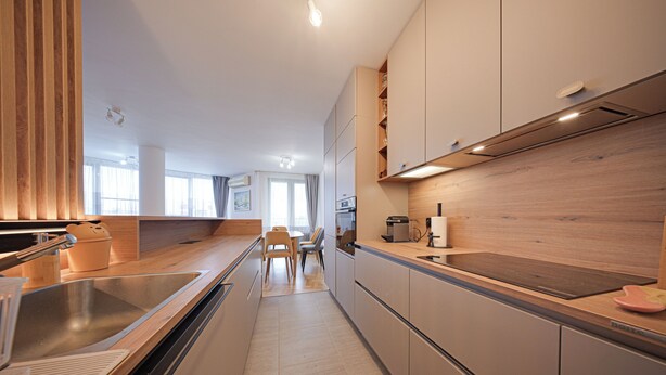 A modern kitchen with wooden cabinets, a stainless steel sink, and a dining area with a table and chairs. - Spacious, Comfortable & Purpose-Driven — An Ideal Sofia Stay (Sofia)