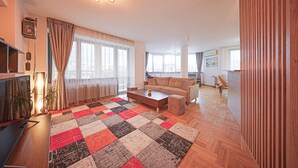 A modern living room with a large window, a sofa, a coffee table, and a television. - Spacious, Comfortable & Purpose-Driven — An Ideal Sofia Stay (Sofia)