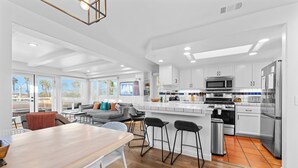 Una cocina moderna con armarios blancos, electrodomésticos de acero inoxidable y una mesa de comedor de madera.