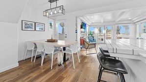 Una cocina moderna con una isla grande, armarios blancos y un comedor con sillas blancas.
