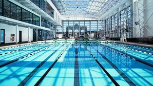 Una amplia piscina interior con varias pistas de natación, techo de cristal y un diseño arquitectónico moderno.