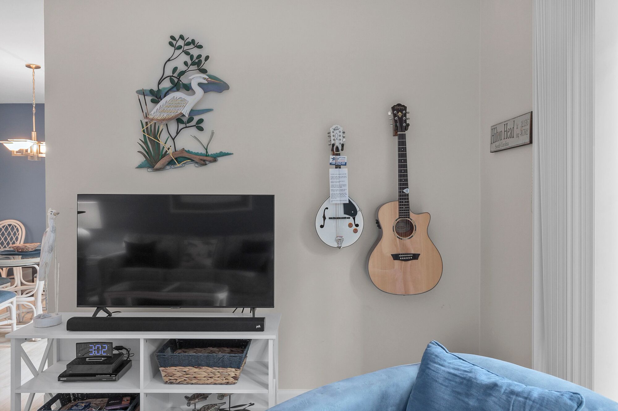 Una sala de estar con un televisor de pantalla plana, una guitarra y un adorno de pared.