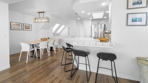 Una cucina moderna con mobili bianchi, un piano di lavoro in legno e un forno integrato. Sono presenti due sgabelli da bar e un tavolo con sedie.