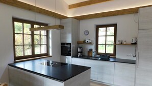 A modern kitchen with a central island, built-in appliances, and large windows.