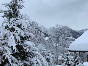 Un paysage de montagne enneigé, avec des arbres et un bâtiment au premier plan.