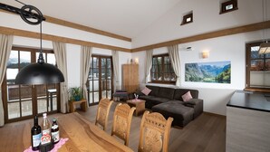A spacious living room with a wooden dining table, a sofa, and a kitchen area.