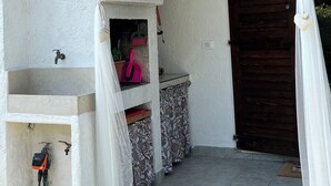 Un balcón con un lavabo blanco, un cepillo rosa y una puerta de madera.