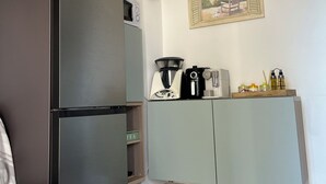 Una habitación compacta con una cama, kitchenette y un pequeño rincón de descanso.