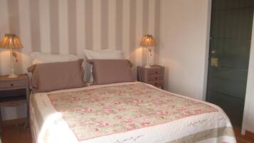 Une chambre à coucher avec un lit, deux tables de chevet avec des lampes, une commode et un mur à rayures.