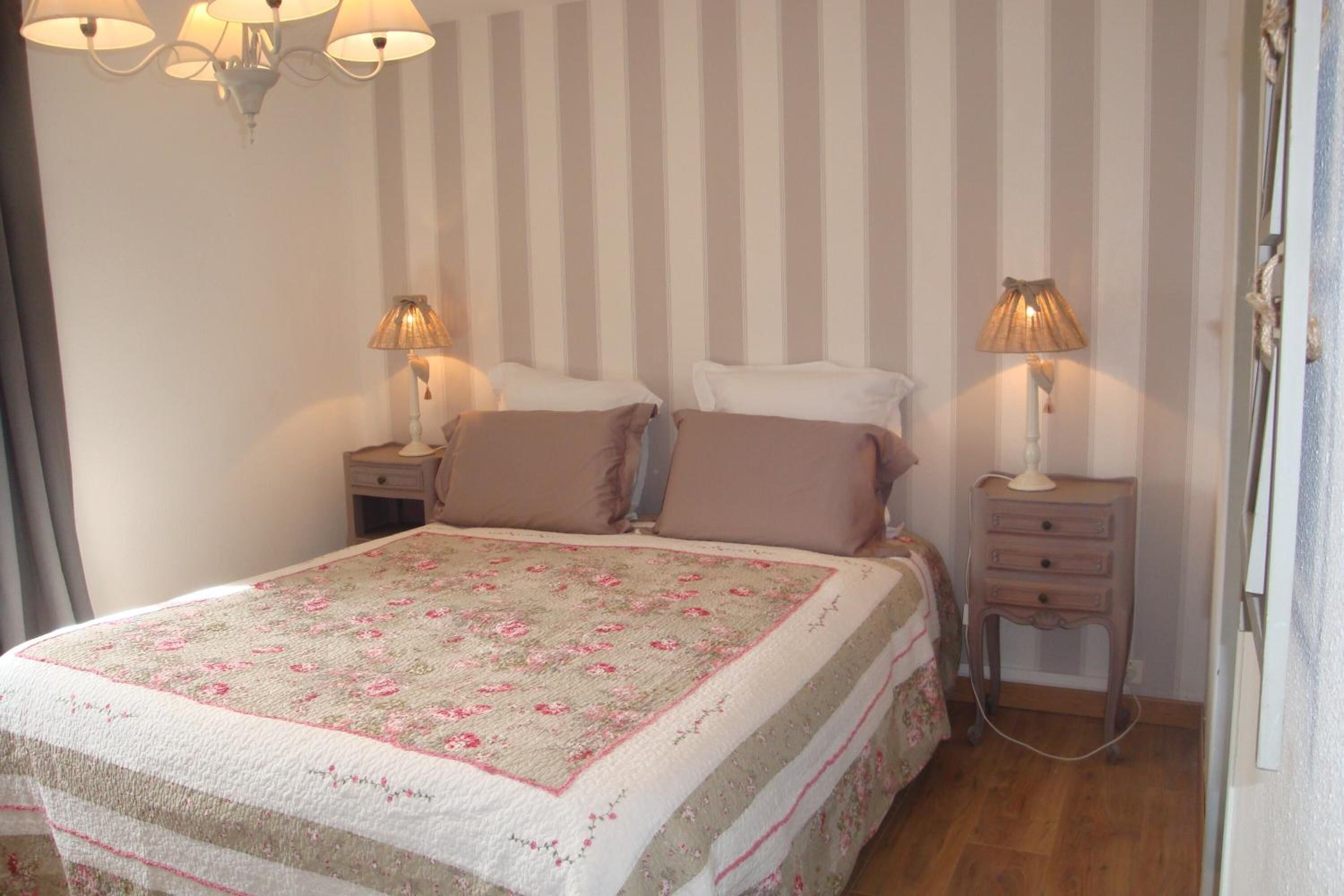 A bedroom with a bed, two bedside tables, lamps, and a striped wall.