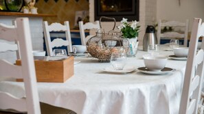 Een eettafel gedekt met een witte tafelkleed, borden, kommen en glazen.