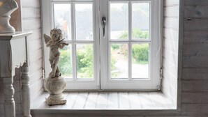 Una habitación con un ventanal grande, una estatua de ángel y suelo de madera.