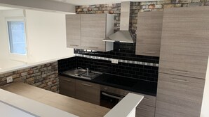 Een moderne keuken met een zwarte achterwand, grijze kastjes en een raam.