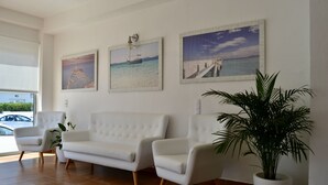 Un interior moderno con un sofá blanco, dos sillones y una planta en maceta.