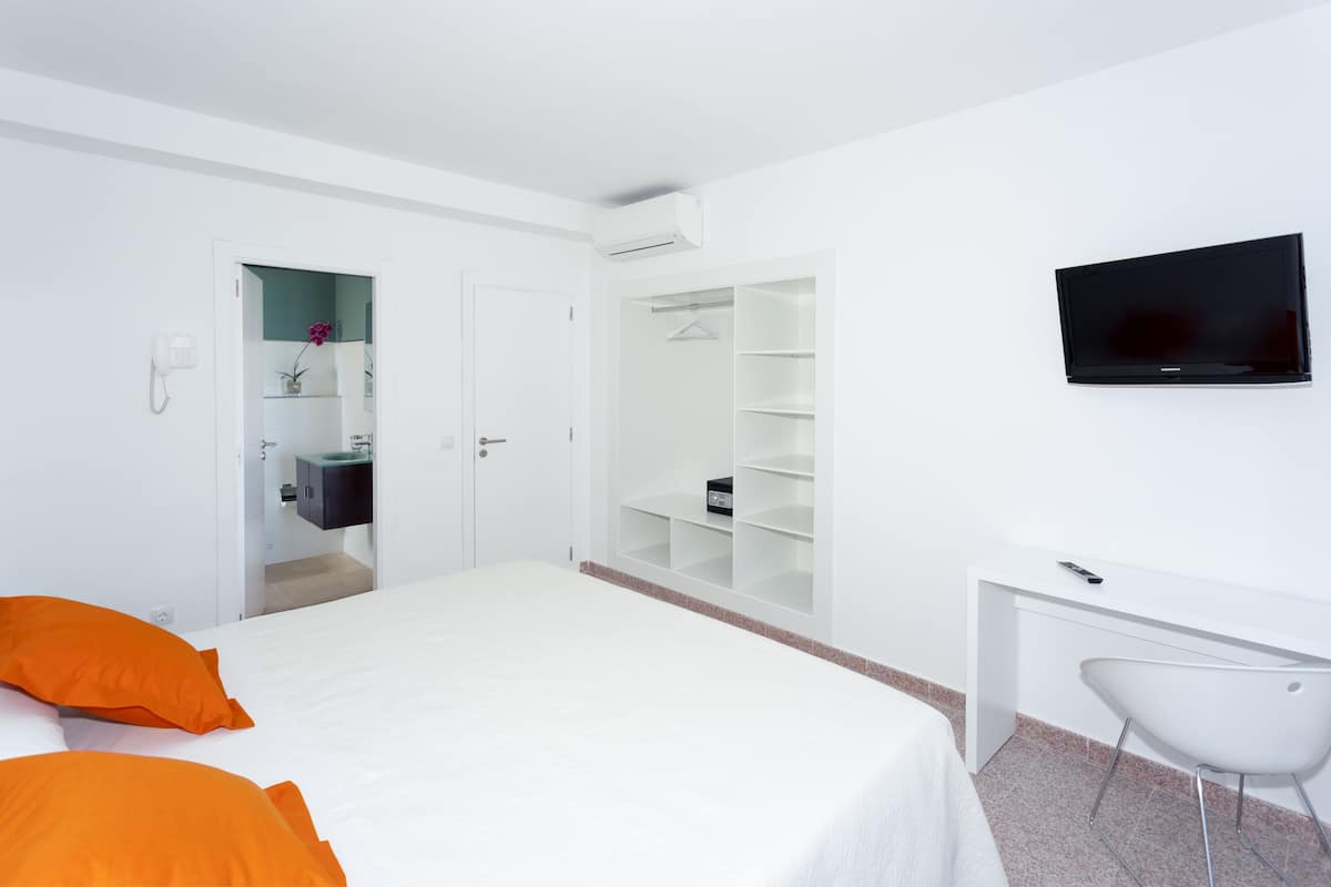 Habitación de hotel con cama, escritorio, silla, televisor, armario y baño.