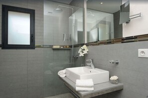 A modern bathroom with a glass shower enclosure, a white sink, and a mirror above the sink. - Rosumarinu Apartment (Figari)