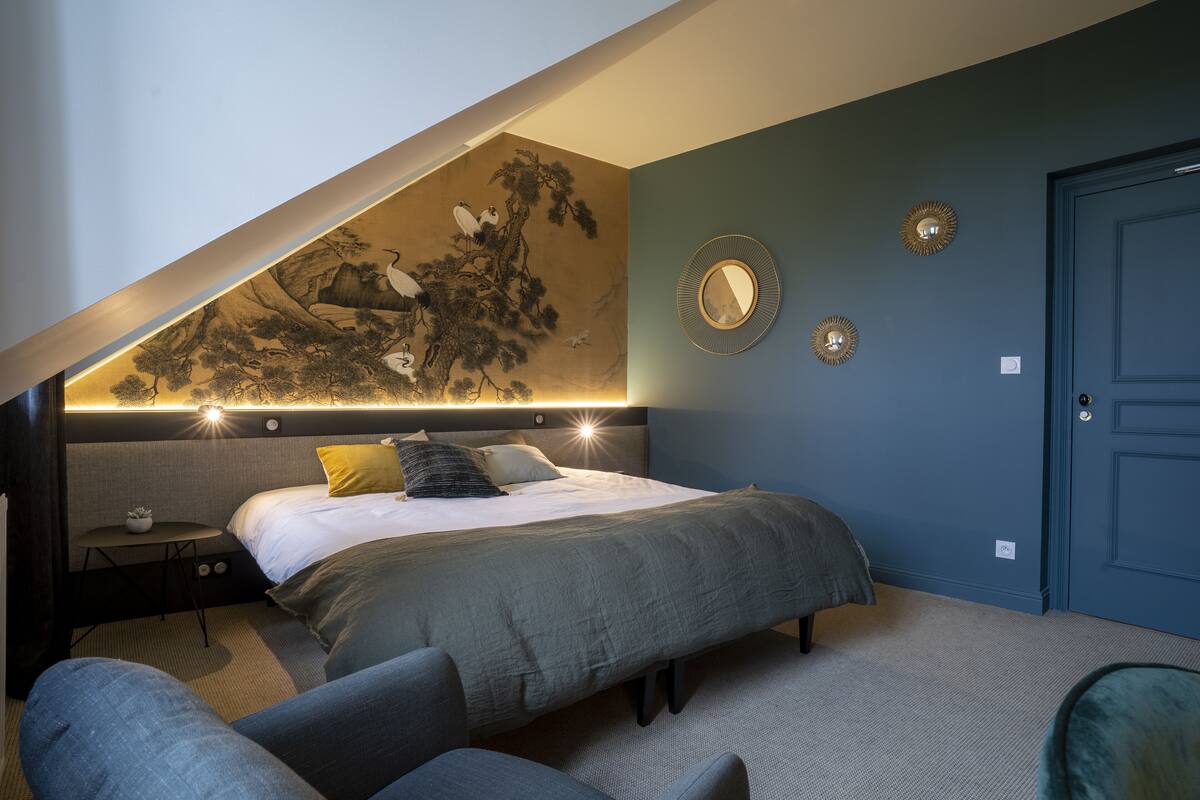A bedroom with a bed, bedside tables, a bench, and a wall with a mural.