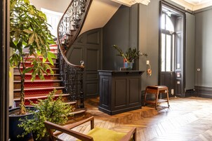 Una escalera con acabado de madera, un mueble de madera oscura y una planta en maceta.