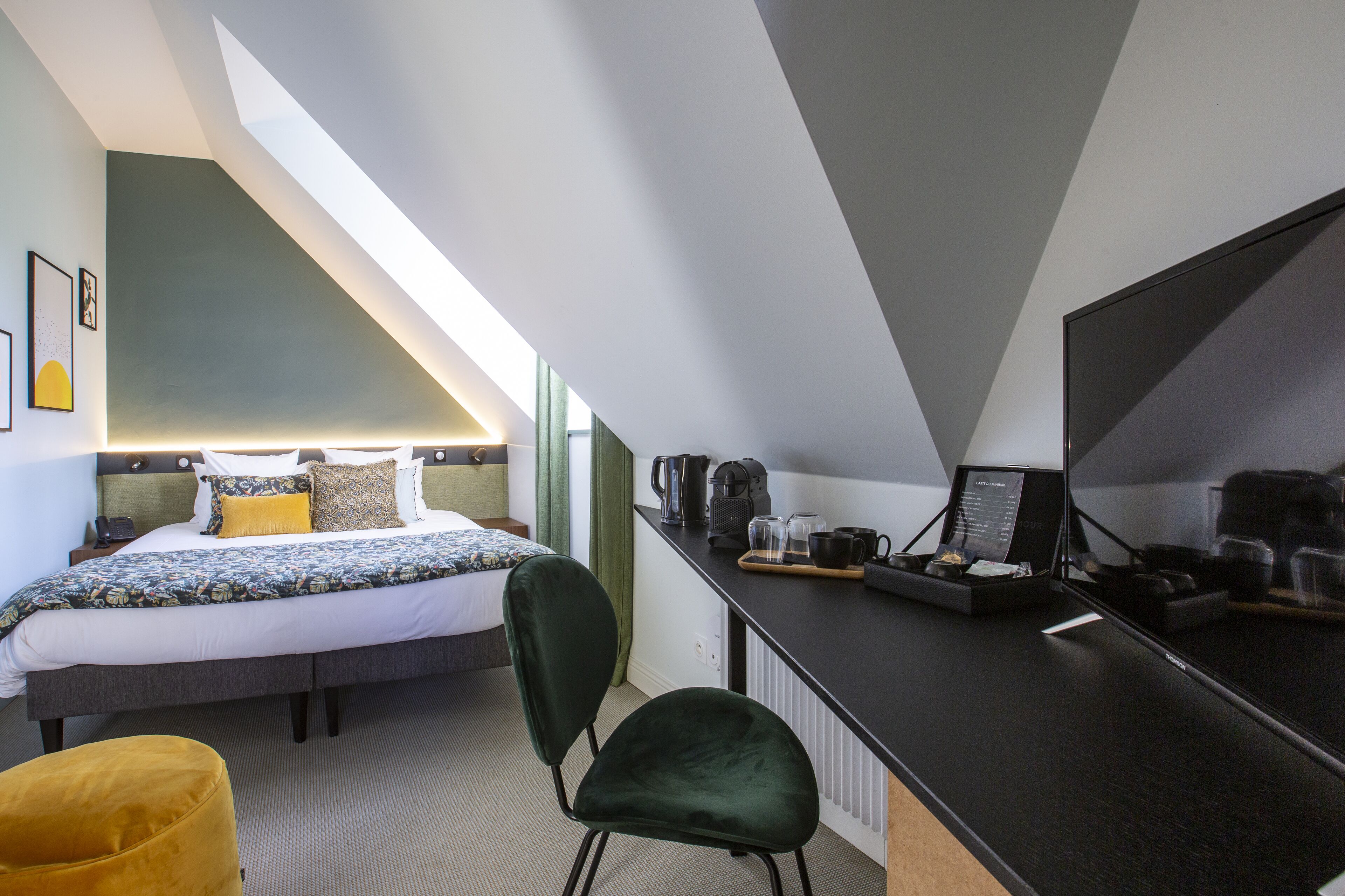 A modern hotel room with a bed, a desk, a chair, and a large mirror.