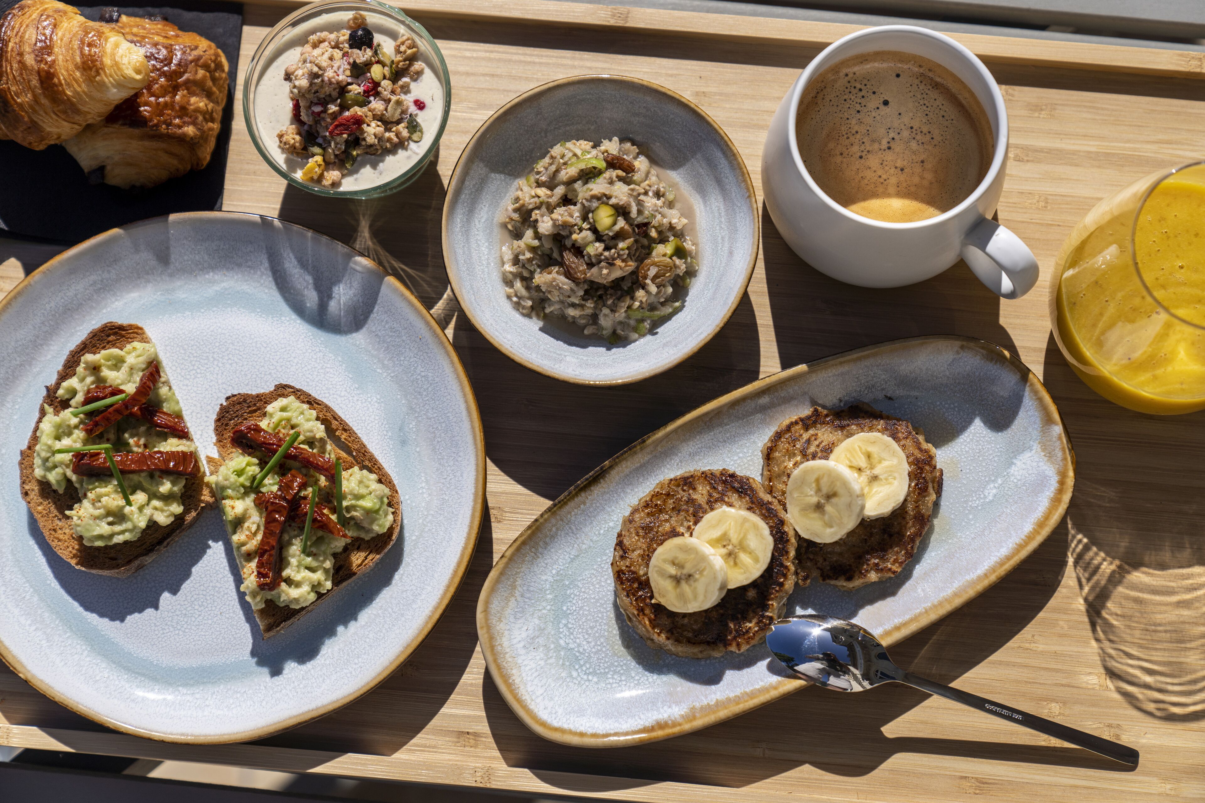 A breakfast tray with croissants, oatmeal, coffee, and toast with banana slices.