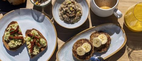 A breakfast tray with croissants, oatmeal, coffee, and toast with banana slices.