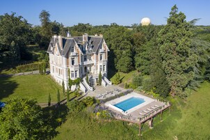 Un edificio grande e histórico con piscina y terraza.