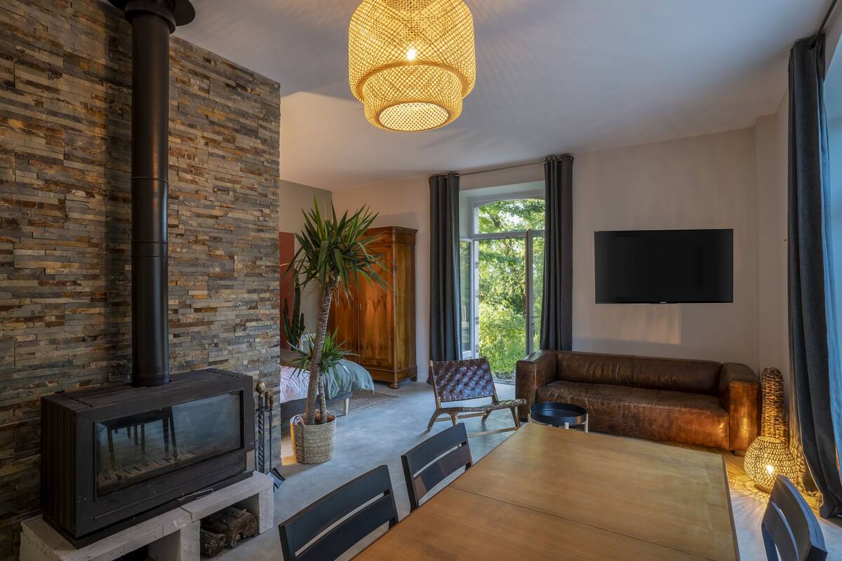 A modern living room with a stone wall, a fireplace, a dining area, and a large window.
