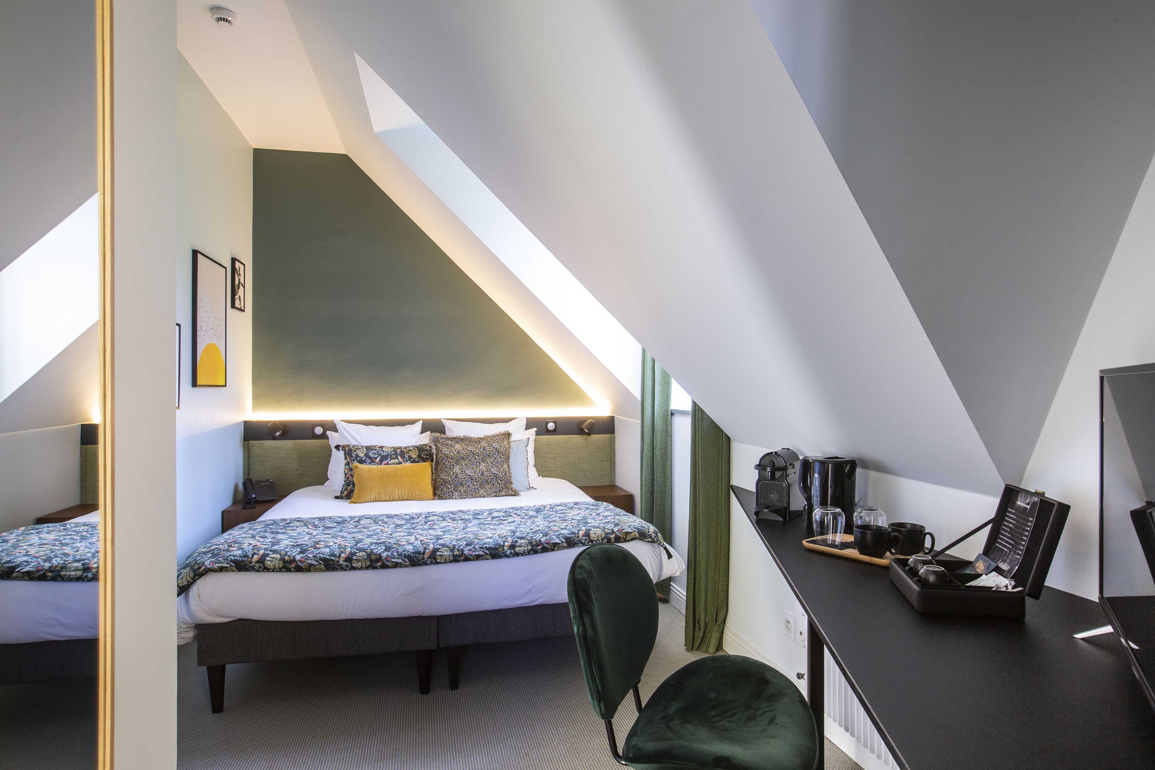 A modern hotel room with a large bed, a desk with a laptop, and a chair.