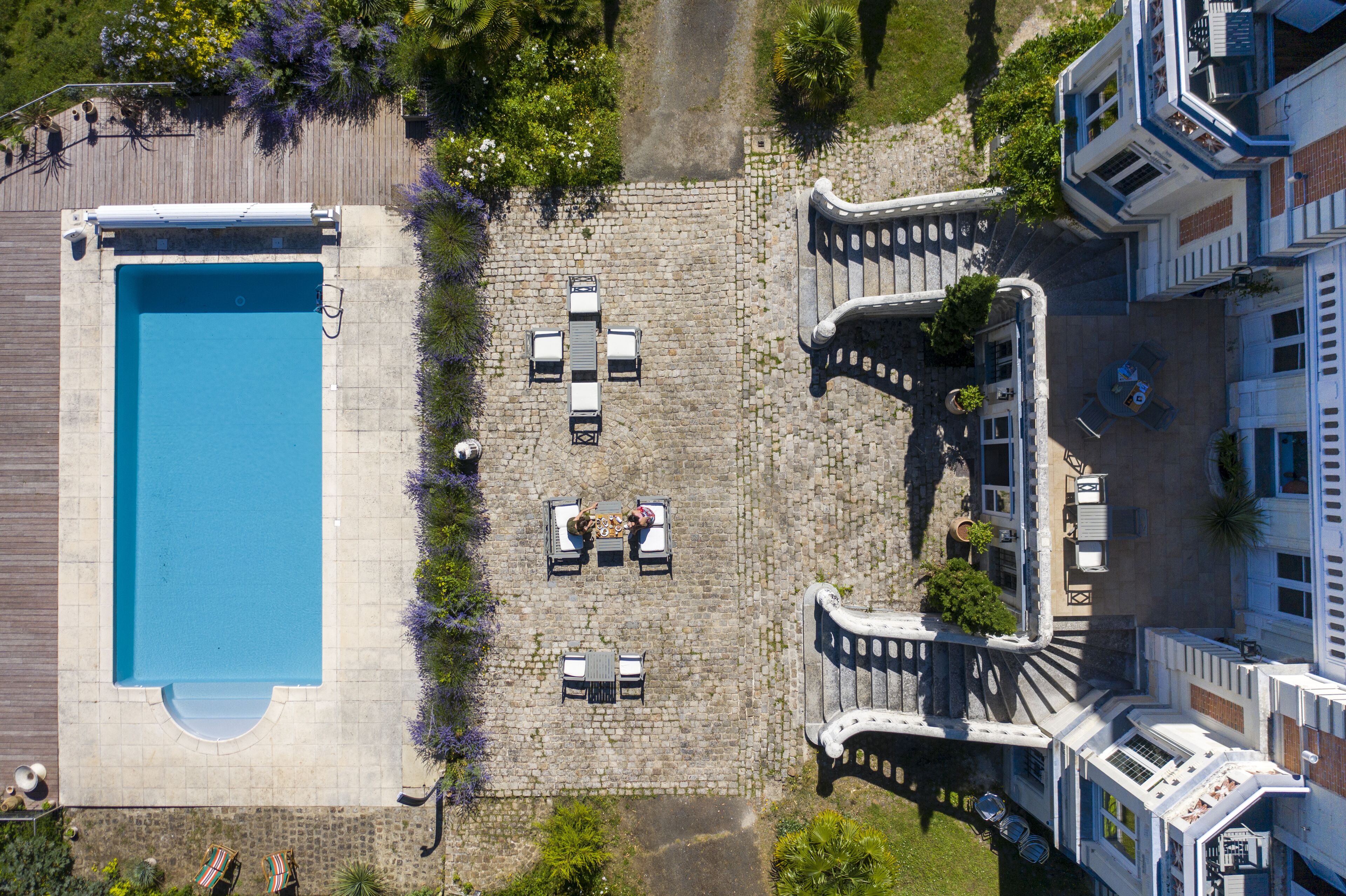 An aerial view of a courtyard with a swimming pool, outdoor seating, and a stone pathway.