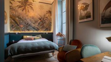 Een slaapkamer met een groot bed, een stoel, een tafel en een muur met een muurschildering.