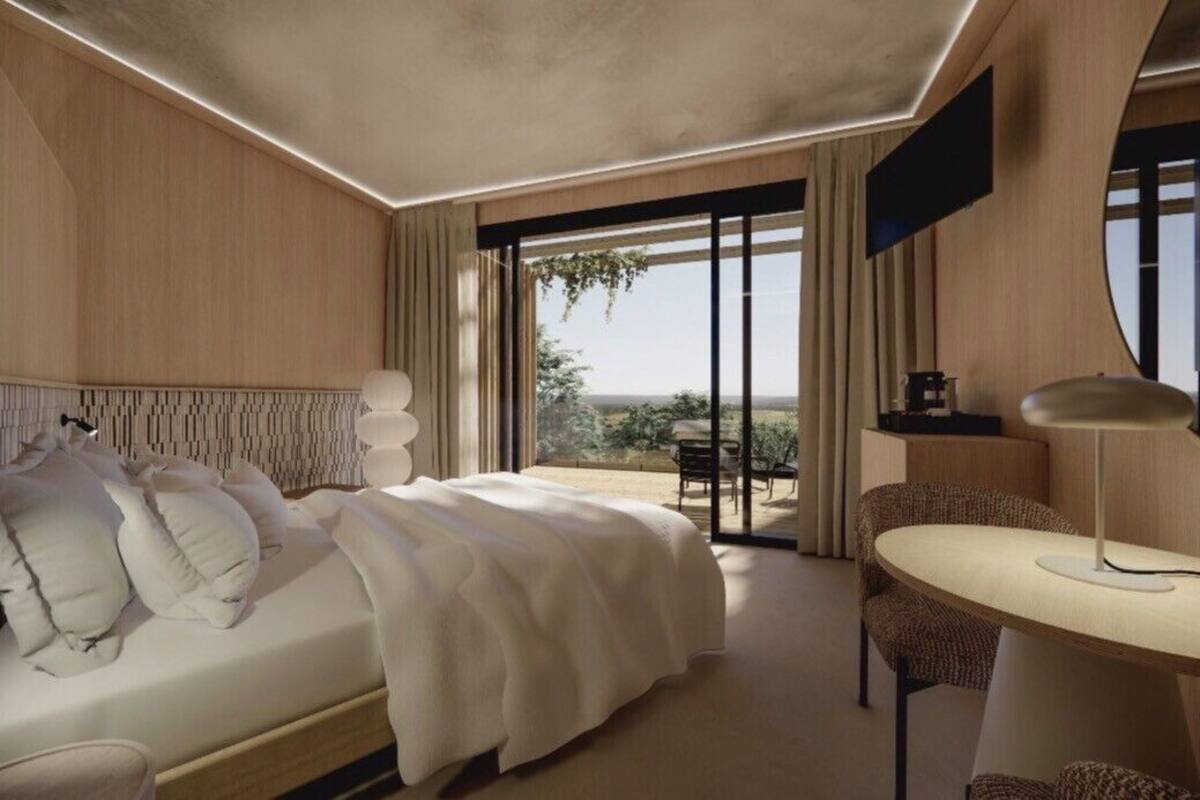 A modern hotel room with a large bed, a round table, and a view of the outdoors.