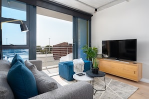 Relax in this stylish living room with a large sofa, flat-screen TV, and city view.