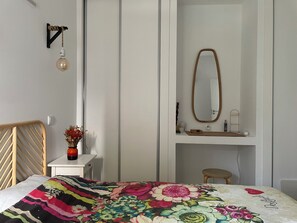 A bedroom with a bed, a bedside table with a vase, a mirror, and a hanging light fixture. - Fantastic House: ideal for 2 couples and their children, ideal for telework (Almancil)