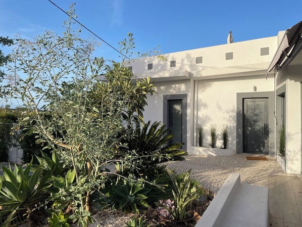 A modern building with a flat roof, a paved entrance, and a gravel pathway leading to the door.
