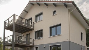 A two-story building with a balcony on the upper floor, a flat roof, and a light-colored facade. - Quiet apartment with terrace for 6 people, 3 bedrooms. (Gérardmer)