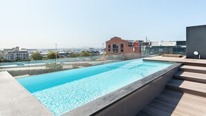 A rooftop swimming pool with a clear view of the cityscape in the background.