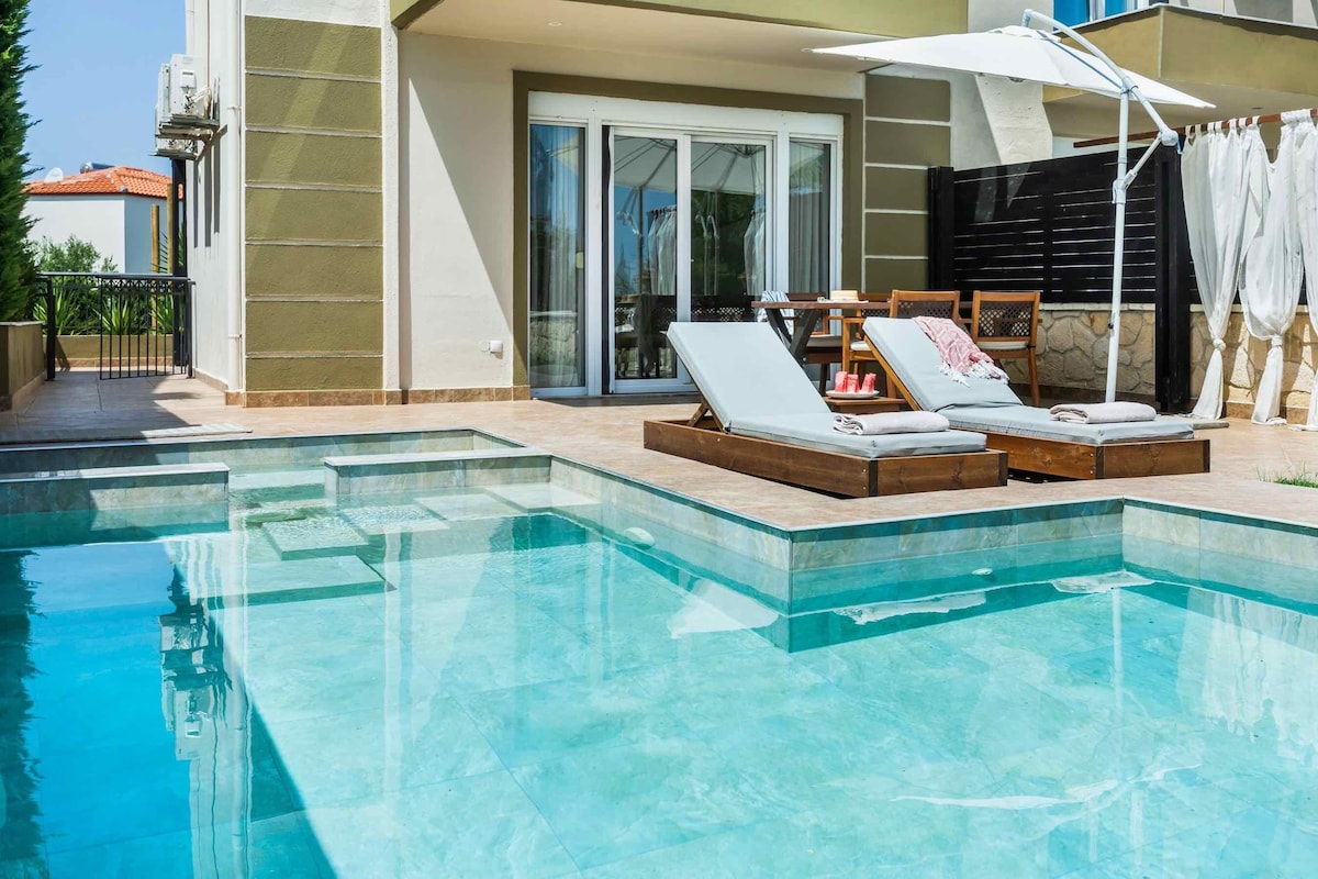A swimming pool with lounge chairs and a sun umbrella.