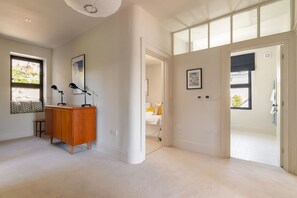 A spacious room with a large window, a wooden cabinet, and a door leading to another room. - Two Guns (Kingswear)