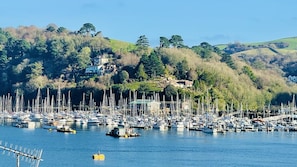 A marina with numerous boats docked, surrounded by hills and a few buildings in the background.
