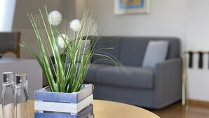 A living room with a grey sofa, a wooden coffee table, and a plant in a wooden crate. - Pension am Meer (Ostseebad Baabe)