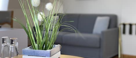 A living room with a grey sofa, a wooden coffee table, and a plant in a wooden crate.