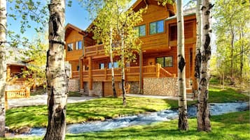 Une cabane en rondins avec des fondations en pierre, des balcons en bois et un mur en pierre.