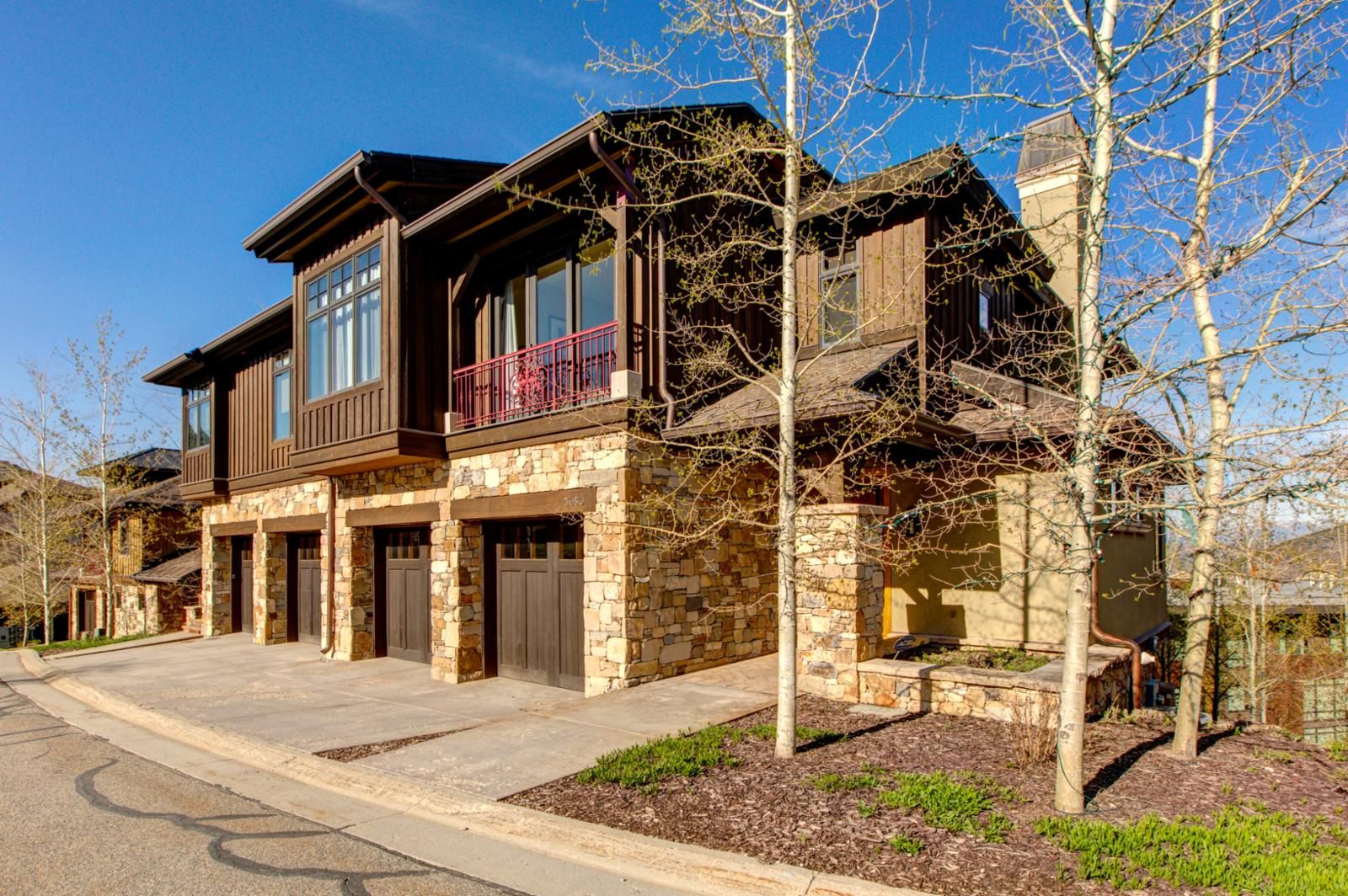 A two-story house with a stone facade, large windows, and a balcony.