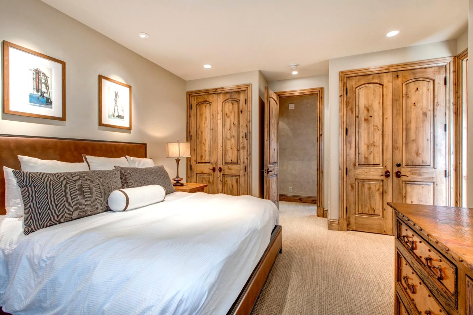 Une chambre à coucher avec un grand lit, une armoire en bois et une table de chevet avec une lampe.