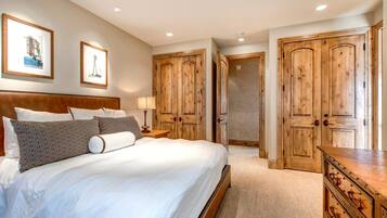 Une chambre à coucher avec un grand lit, une armoire en bois et une table de chevet avec une lampe.
