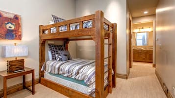 Una cama litera con estructura de madera, una mesita de noche con lámpara, y un cuadro de un oso en la pared.